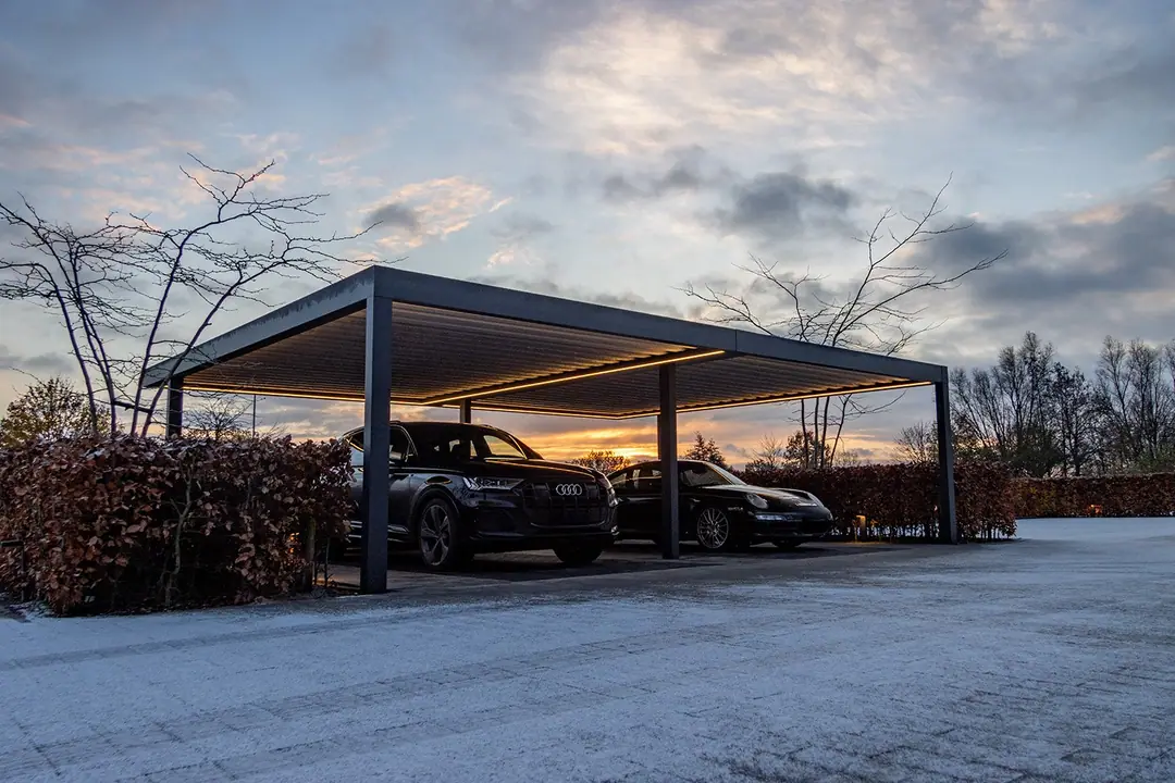 Podwójny Carport w kolorze antracytowym z włączonymi taśmami LED pod dachem o zmierzchu, dwa auta na ośnieżonym podjeździe