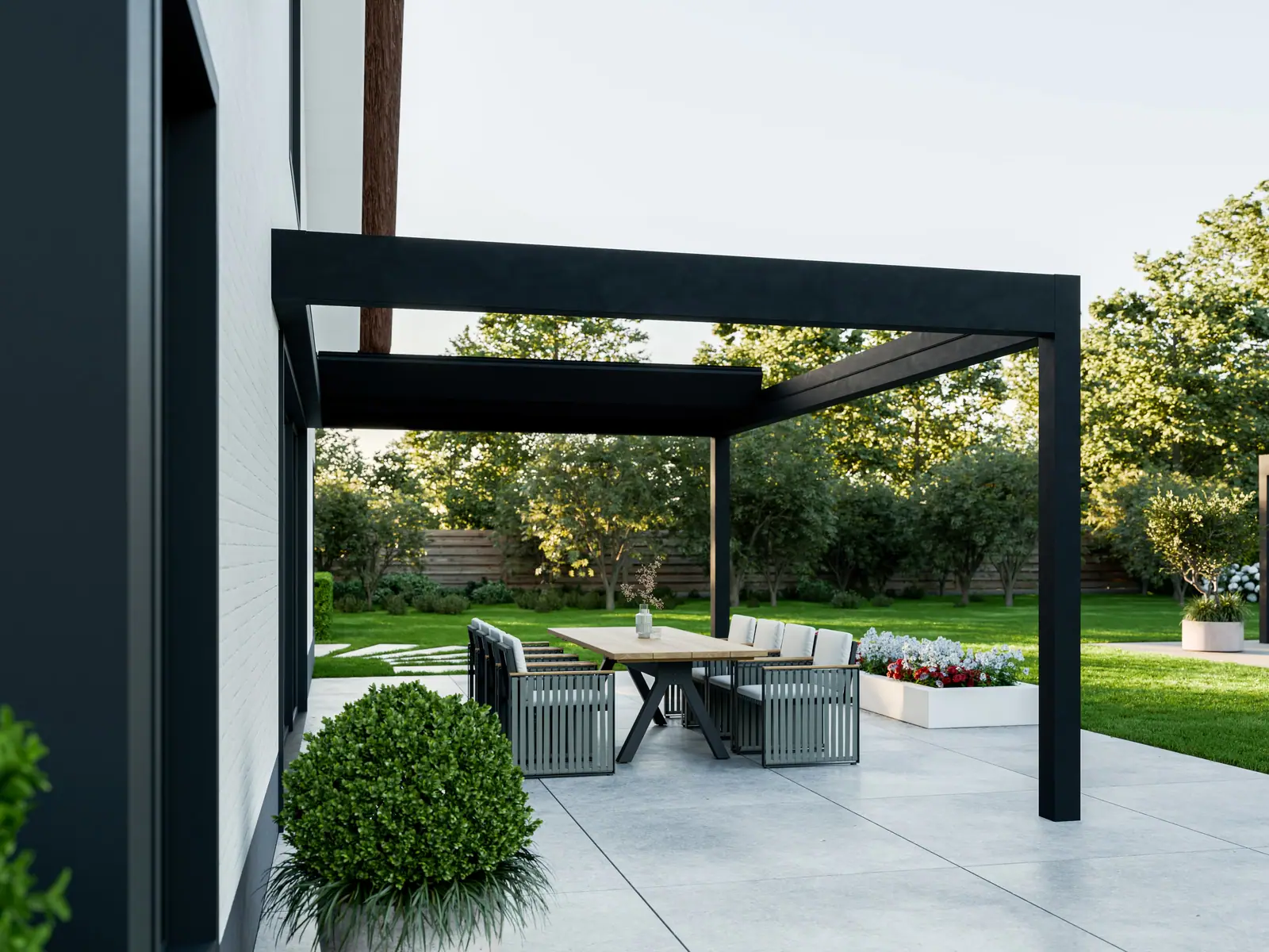 Czarna Pergola Deluxe przy ścianie domu, widok z boku: dach otwarty, lamele złożone w pakiet przy ścianie, pod spodem stół i krzesła ogrodowe