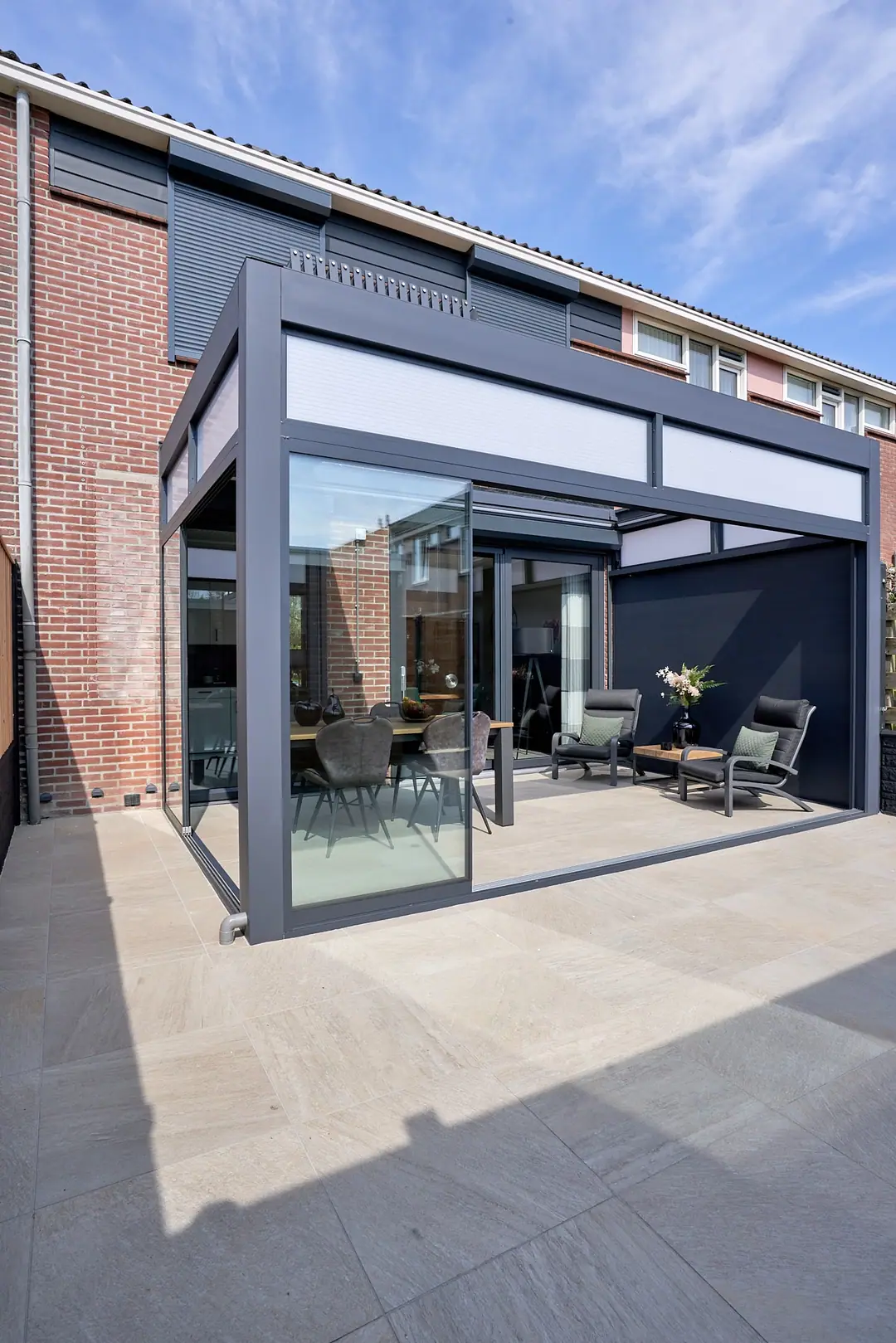 Antracytowa Pergola Deluxe przy domu z cegły, zabudowana szklanymi ścianami przesuwnymi
