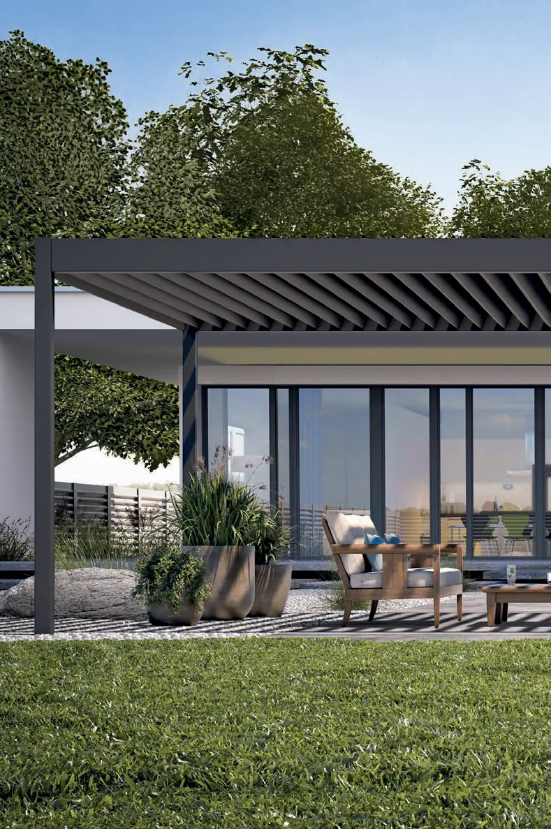 Antracytowa pergola z otwartymi lamelami przed domem z dużymi oknami, pod dachem drewniany fotel i rośliny w donicach